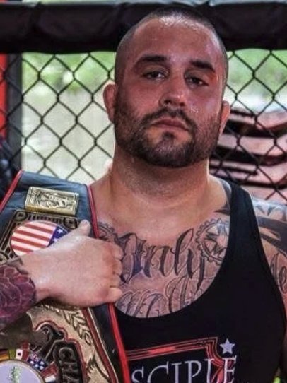Anthony Cordero, Muay Thai coach at Disciple MMA Academy, holding a championship belt