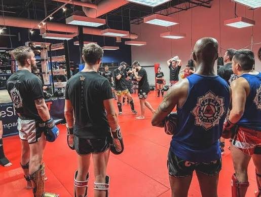 A Muay Thai class watching a technique being demonstrated